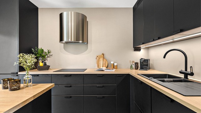 Moderne kjøkken med innredning fra 2020. Benkeplate med laminert overflate. Nedfelt kjøkkenvask med armatur. Benkeskapsbelysning og stikkontakter over kjøkkenbenk. Integrert stekeovn, platetopp, oppvaskmaskin, mikrobølgeovn og kjøleskap med fryser.