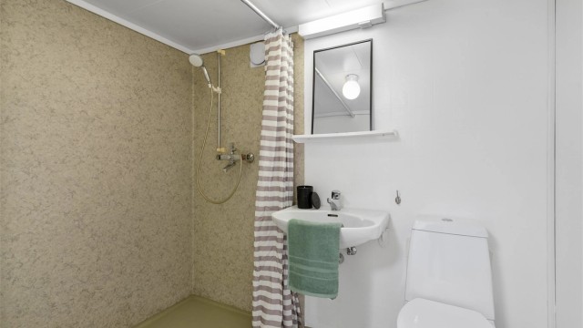 Bad i kjeller er av enkel standard. Dusjnisje, toalett, enkel servant, belegg på gulv og i dusjsone.
