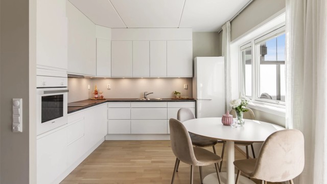 Kjøkkeninnredning fra Sigdal med slette fronter og laminert benkeplate, utstyrt med integrert stekeovn, induksjonstopp og oppvaskmaskin.