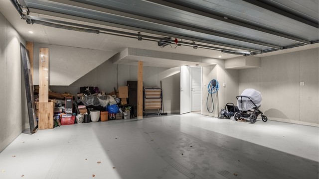 Integrert garasje med støpt betongdekke, leddport med elektrisk portåpner og direkte inngang til boligen.