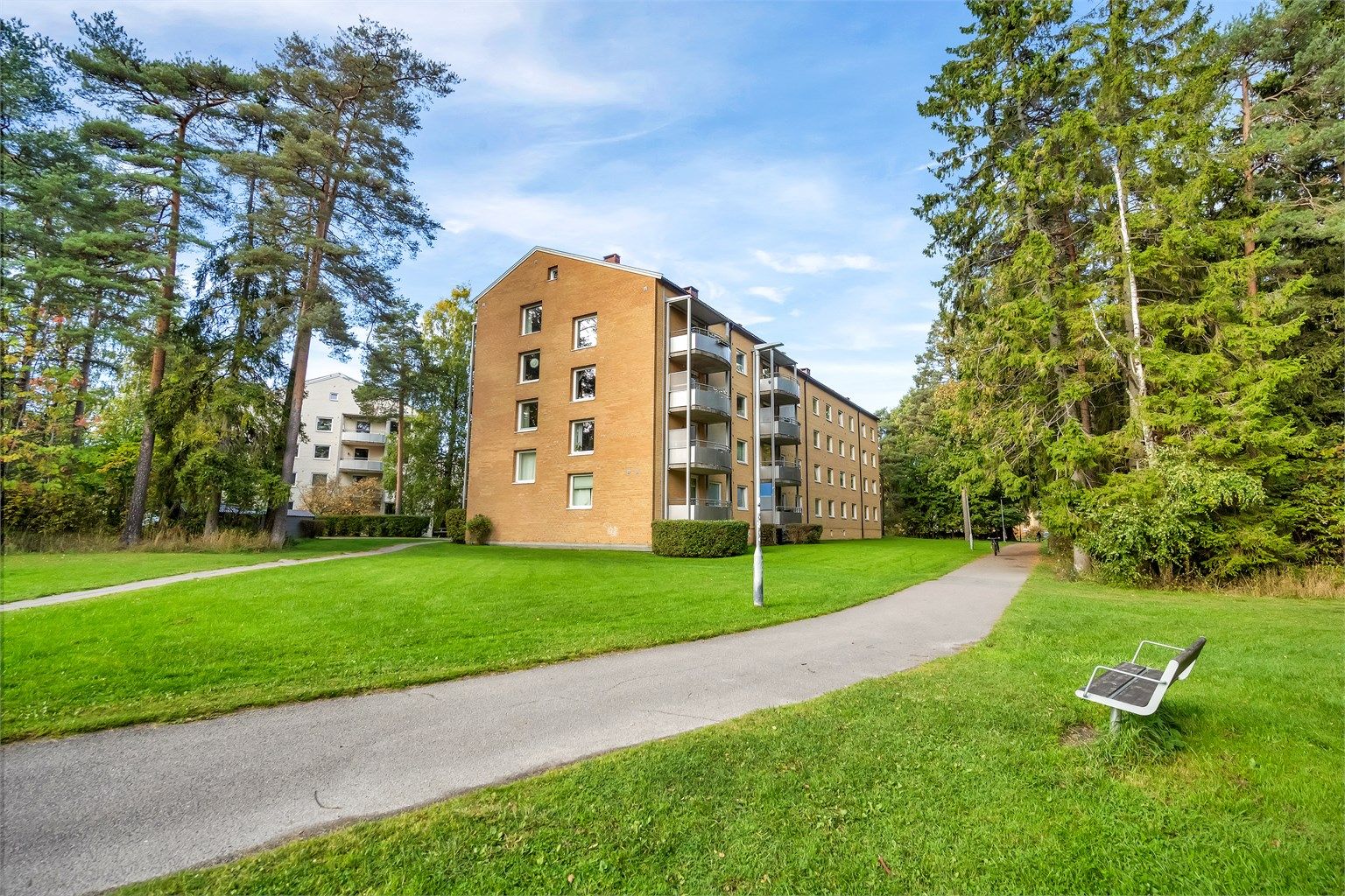 Borettslaget består av teglsteinsblokker plassert i et frodig og grønt parklandskap.