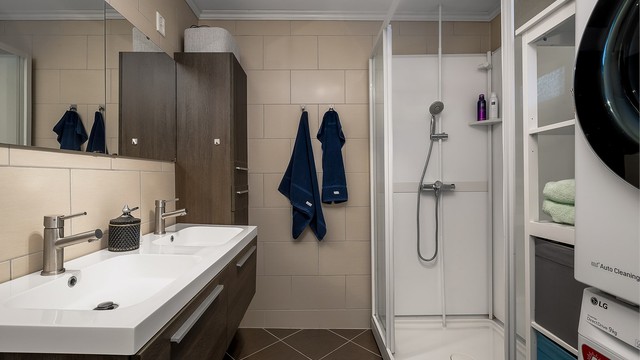 Badet er innredet med baderoms innredning med slette fronter og heldekkende servant, dusjkabinett, toalett og opplegg til vaskemaskin.