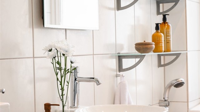 Baderomsinnredning med servant og speil. Badet har innfelte downlights i himlingen med malt panel.