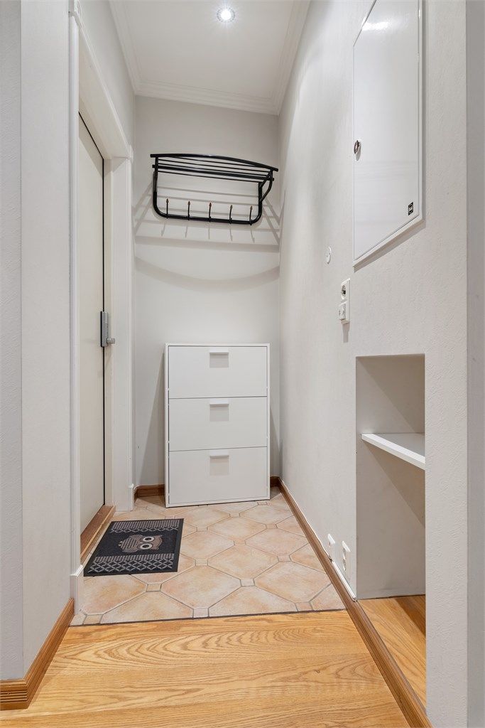 Praktisk entré med flislagt gulv og gulvvarme. Legg og merke til den plassbygde oppbevaringsløsningen for sko