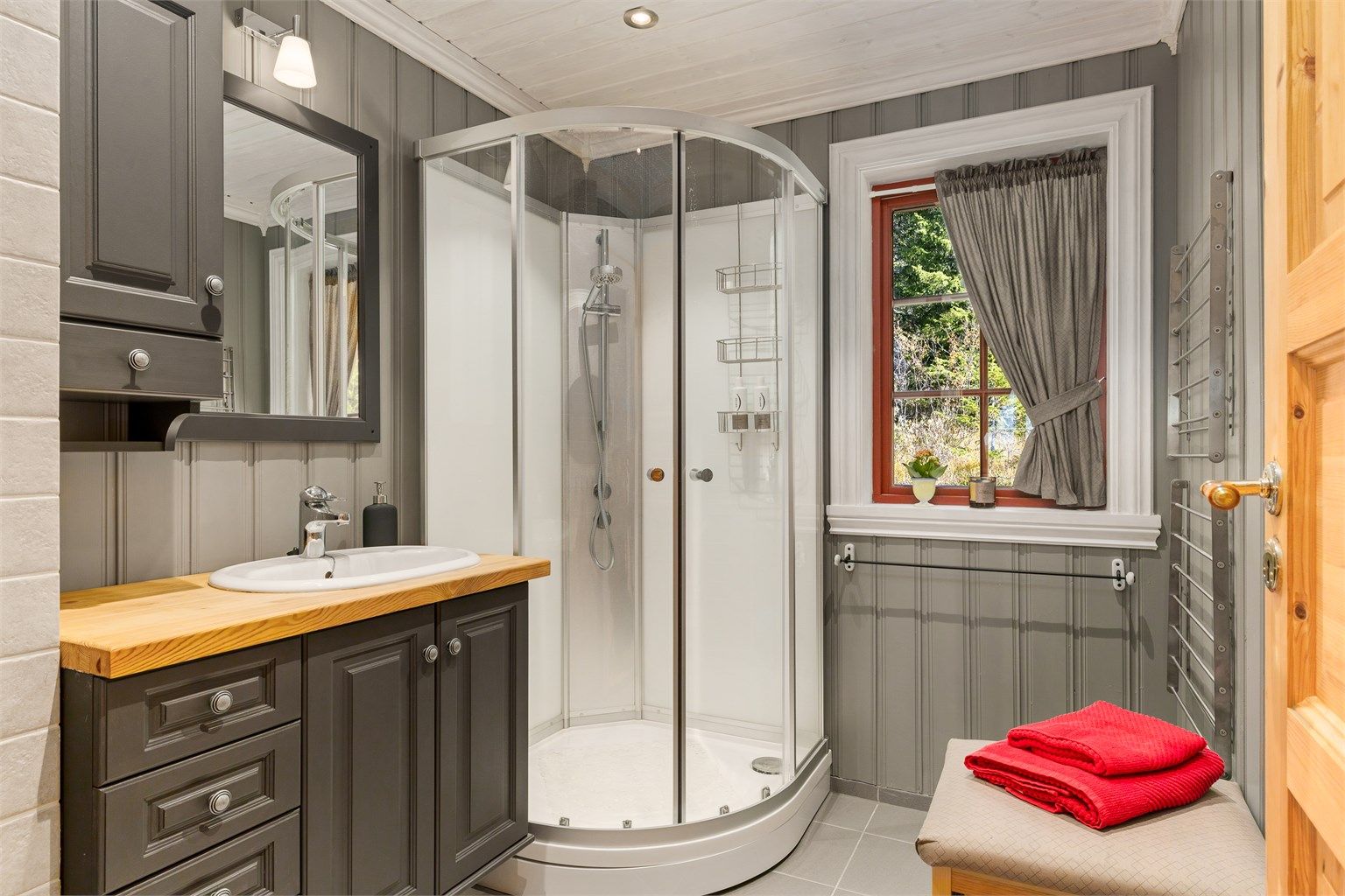 Bad i hoveddelen med dusjkabinett og heltre benkeplate.