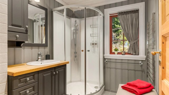 Bad i hoveddelen med dusjkabinett og heltre benkeplate.