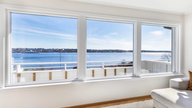 Rekken av store vinduer ivaretar den flotte sjøutsikten og gir stuen gode lysforhold dagen gjennom. Alle ble byttet ut i 2022.