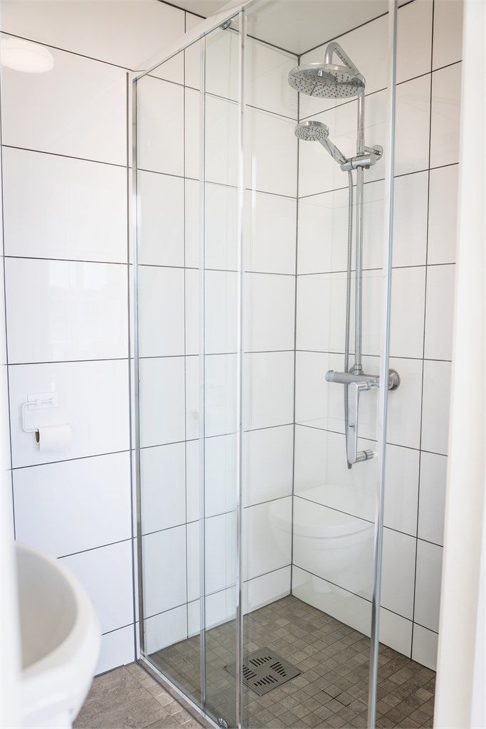 Badet har dusjhjørne med skyvedørsramme og veggmontert regnfallsdusj.