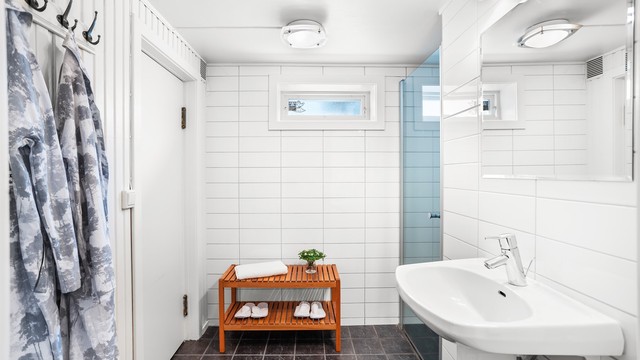 Badet i kjelleren består videre av flislagt gulv med varme, vegghengt servant, speil med overlys og en dusjnisje, i tillegg til inngang til badstuen her.