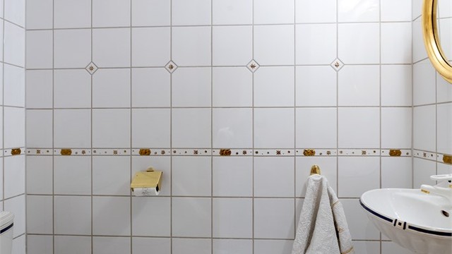Toalettrommet har flislagt gulv og vegger med dekorborde.