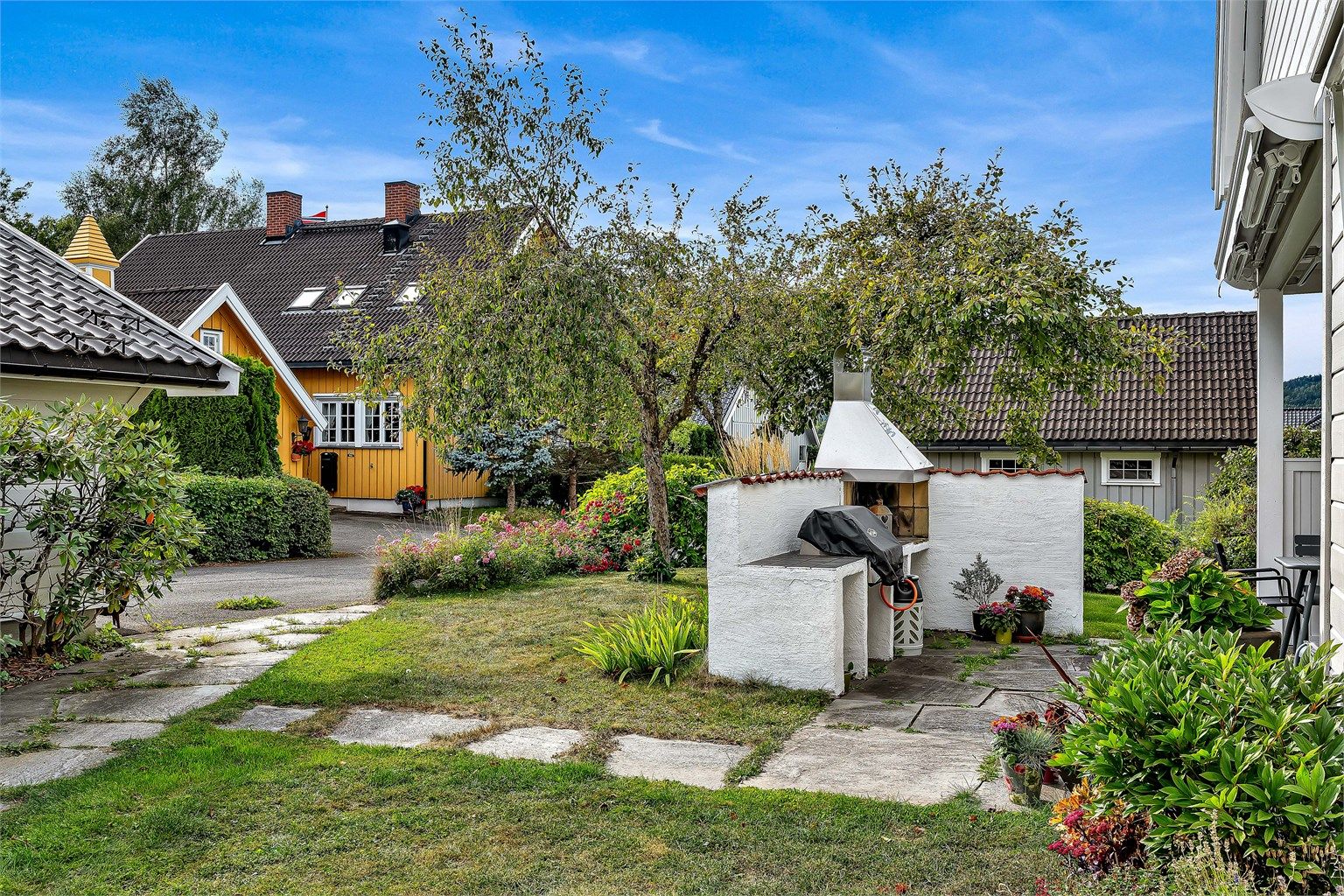 Hagen er pent opparbeidet med plen, beplantning og frukttrær (epler og plommer, samt ripsbusker)