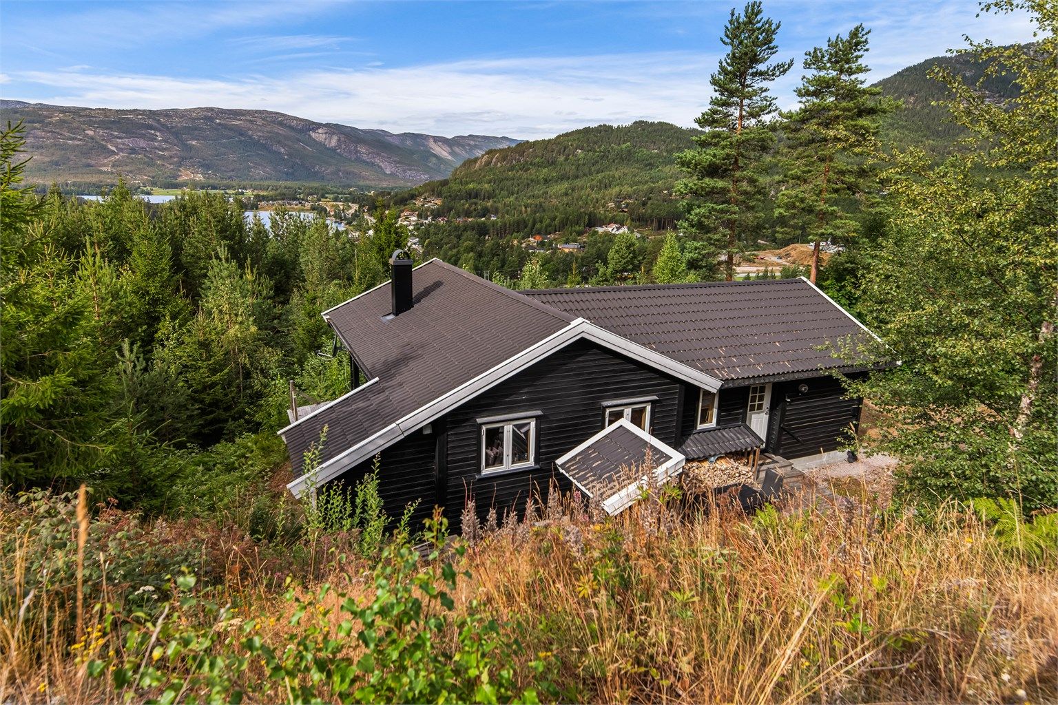 Hytta ligger høyt og fritt i terrenget, omkranset av natur.