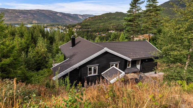 Hytta ligger høyt og fritt i terrenget, omkranset av natur.