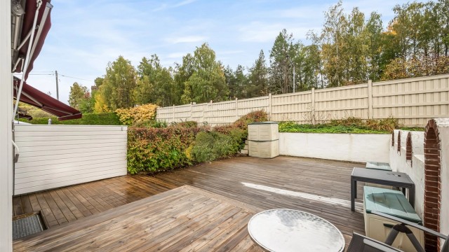 Sydvestvendt fasade med markiser og utgang fra kjøkkenet via skyvedør. Foto: Martine Eren Jacobsen