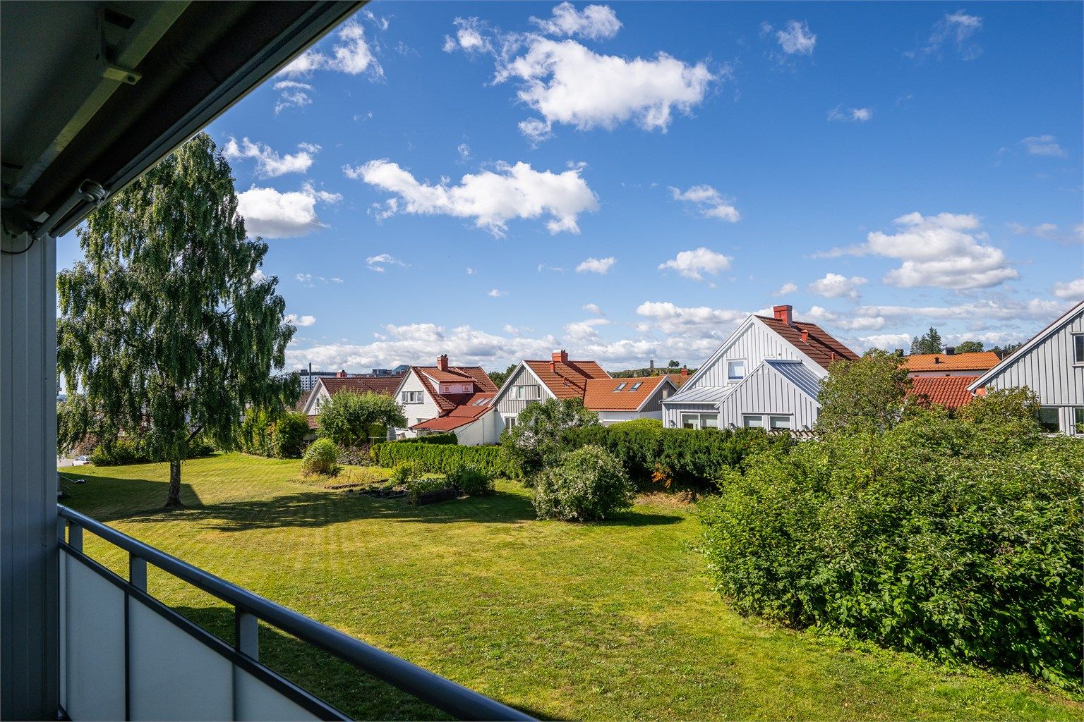 Fra balkongen ser man ut over borettslagets store, grønne fellesarealer.
