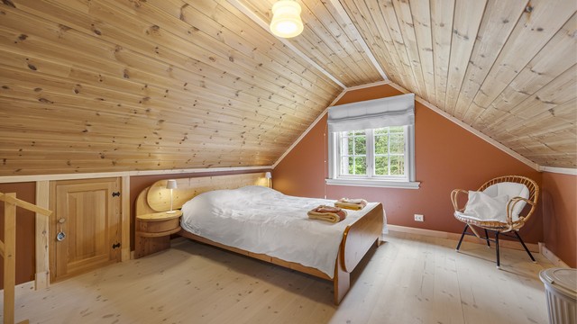 Soverom på loftet med panel i himling og heltre gulv.
