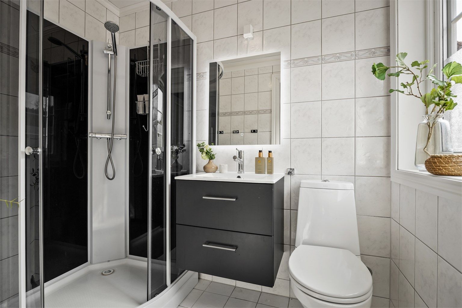 Bad i første etasje med fliser på vegger og varme i gulvet. Innredningen med servant og speil er fra 2016.