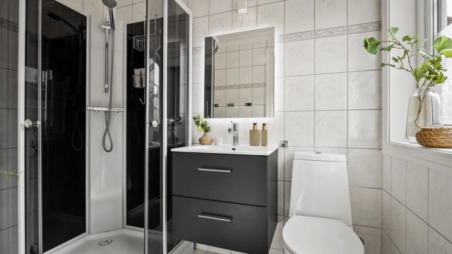 Bad i første etasje med fliser på vegger og varme i gulvet. Innredningen med servant og speil er fra 2016.