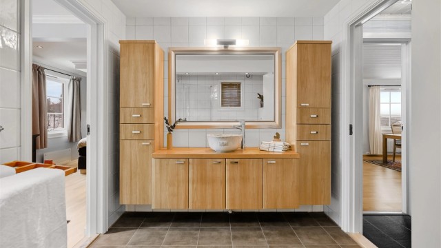 Badet i første etasje har en vegghengt servant med ovenpåliggende bolleservant og benkeplate i heltre.
