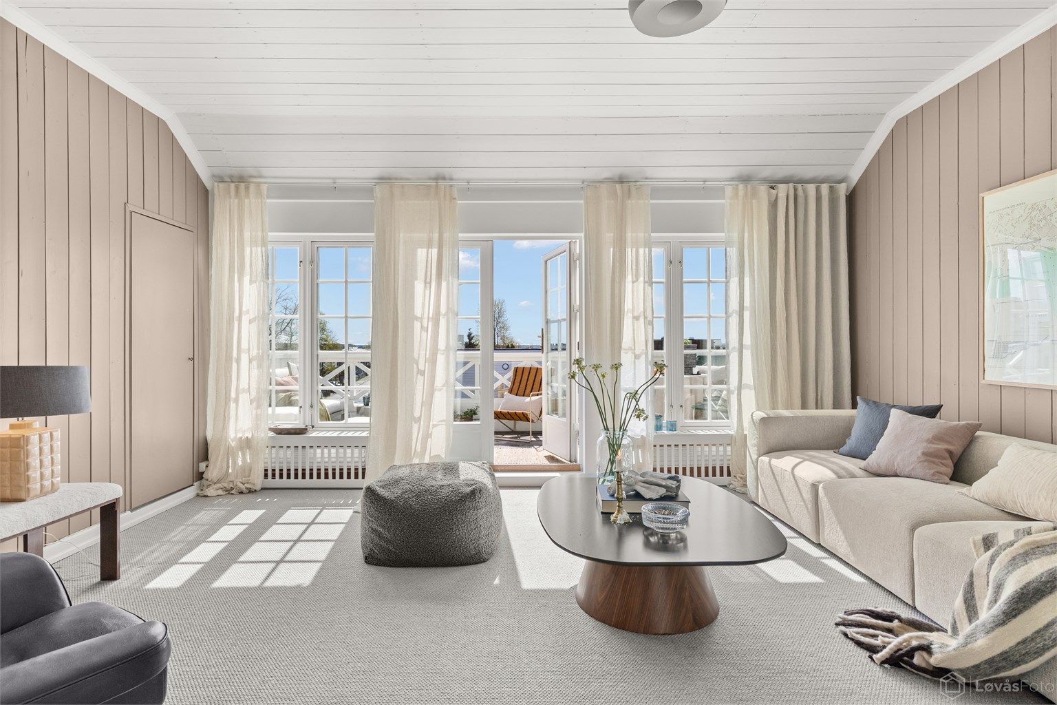 Lys og romslig tv-stue med store sprossede vinduer mot syd