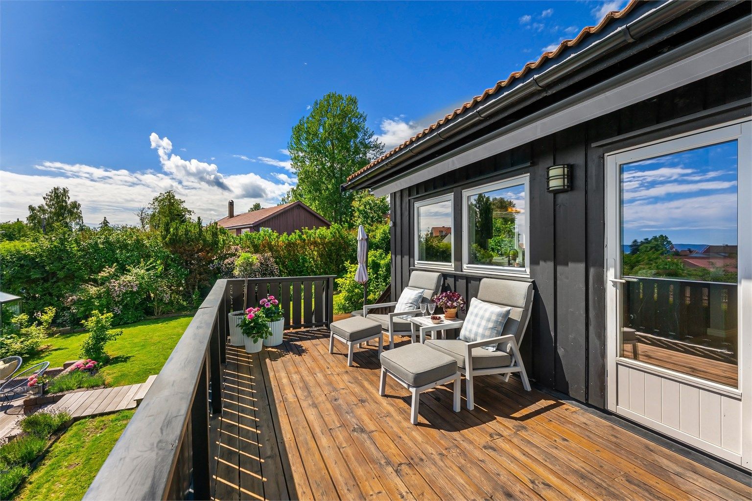 Balkongen har gulv av terrassebord og rekkverk i tre.