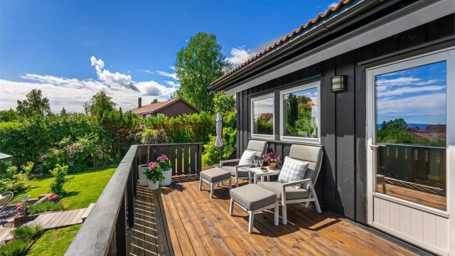 Balkongen har gulv av terrassebord og rekkverk i tre.