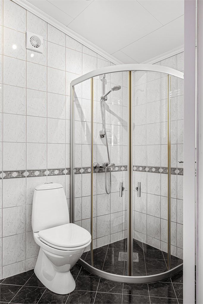 Badet er innredet med dusjhjørne med dører og gulvstående toalett.