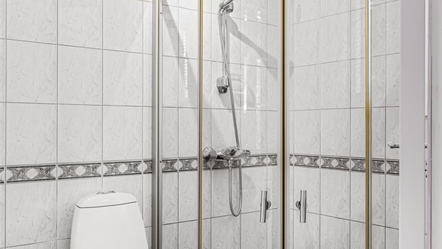 Badet er innredet med dusjhjørne med dører og gulvstående toalett.