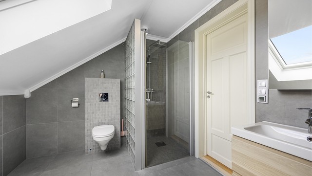 I tillegg til badekar har badet en egen dusjnisje med regndusj og vegghengt toalett.