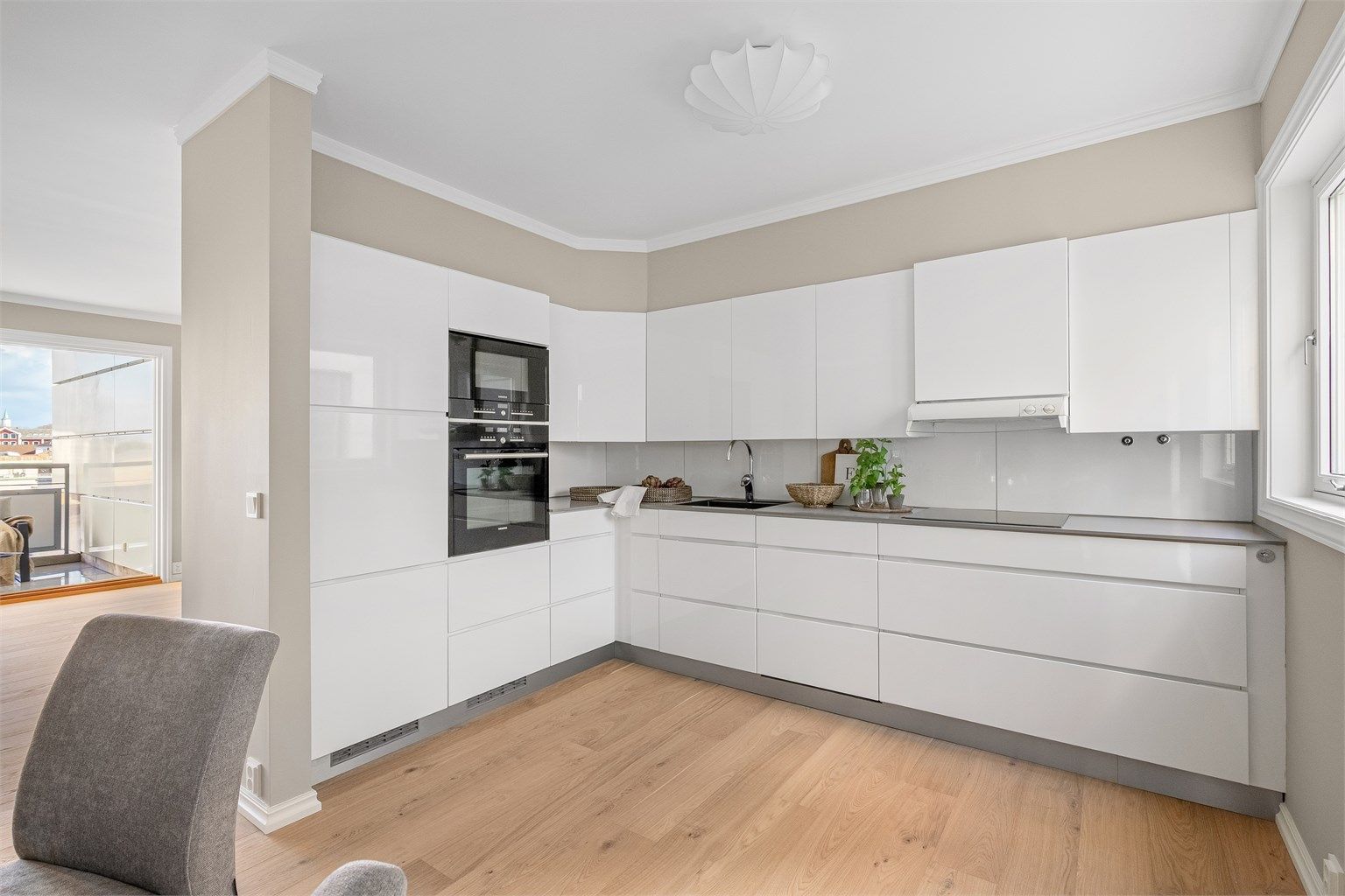 Hvite fronter og grå benkeplate. Integrerte hvitevarer som kjøl-/fryseskap, komfyr, koketopp og oppvaskmaskin. Det er meget bra med skapplass og arbeidsflater på benk.