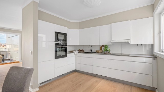 Hvite fronter og grå benkeplate. Integrerte hvitevarer som kjøl-/fryseskap, komfyr, koketopp og oppvaskmaskin. Det er meget bra med skapplass og arbeidsflater på benk.