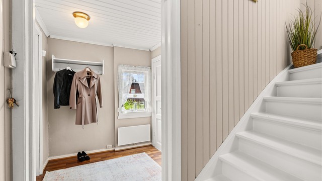 Hyggelig entré med praktisk adkomst til både toalettrom og bod. Hvitmalt tretrapp leder opp til 2. etasje.