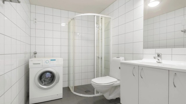 Romslig, flislagt bad fra byggeår med varmekabler i gulv og opplegg for vaskemaskin.