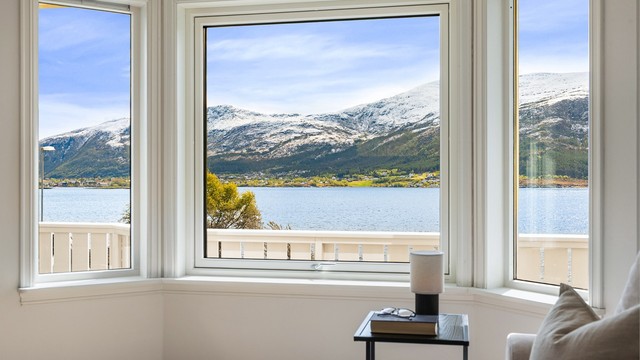 Store vindusflater i stuen rammer inn utsikten mot fjorden og fjellene