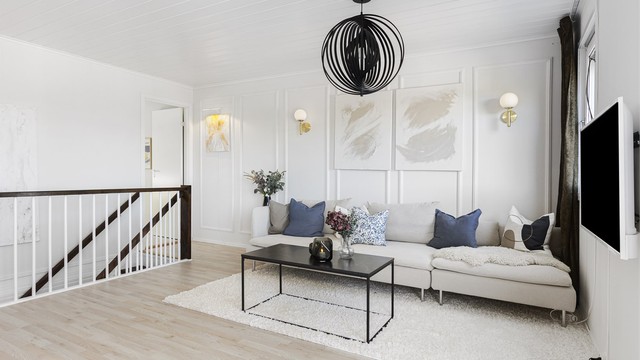 Lys og innbydende stue med laminatgulv og hvitmalte vegger med dekorativ brystpanel.