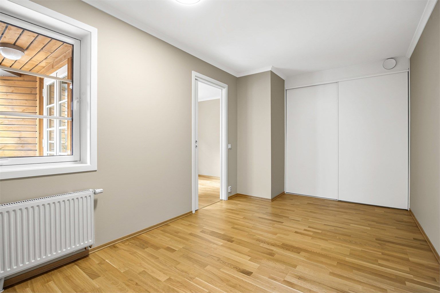 I enden av rommet er det en praktisk innebygd skyvedørsgarderobe i hvit og glatt utførelse. 