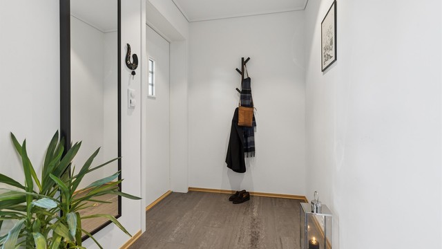 Velkommen inn! Gangen er romslig, med gulvvarme og et stort vinduet som slipper inn rikelig med naturlig lys og skaper et lyst og innbydende førsteinntrykk.