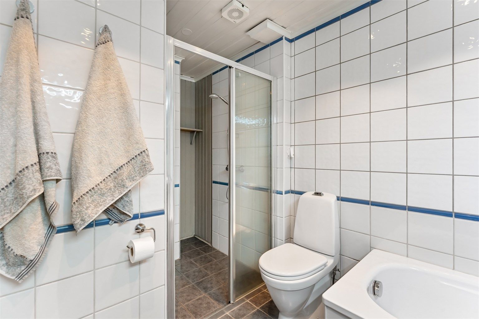 Dusjnisjen har glassvegg og glassdør. Badet har mekanisk avtrekksvifte i himlingen.