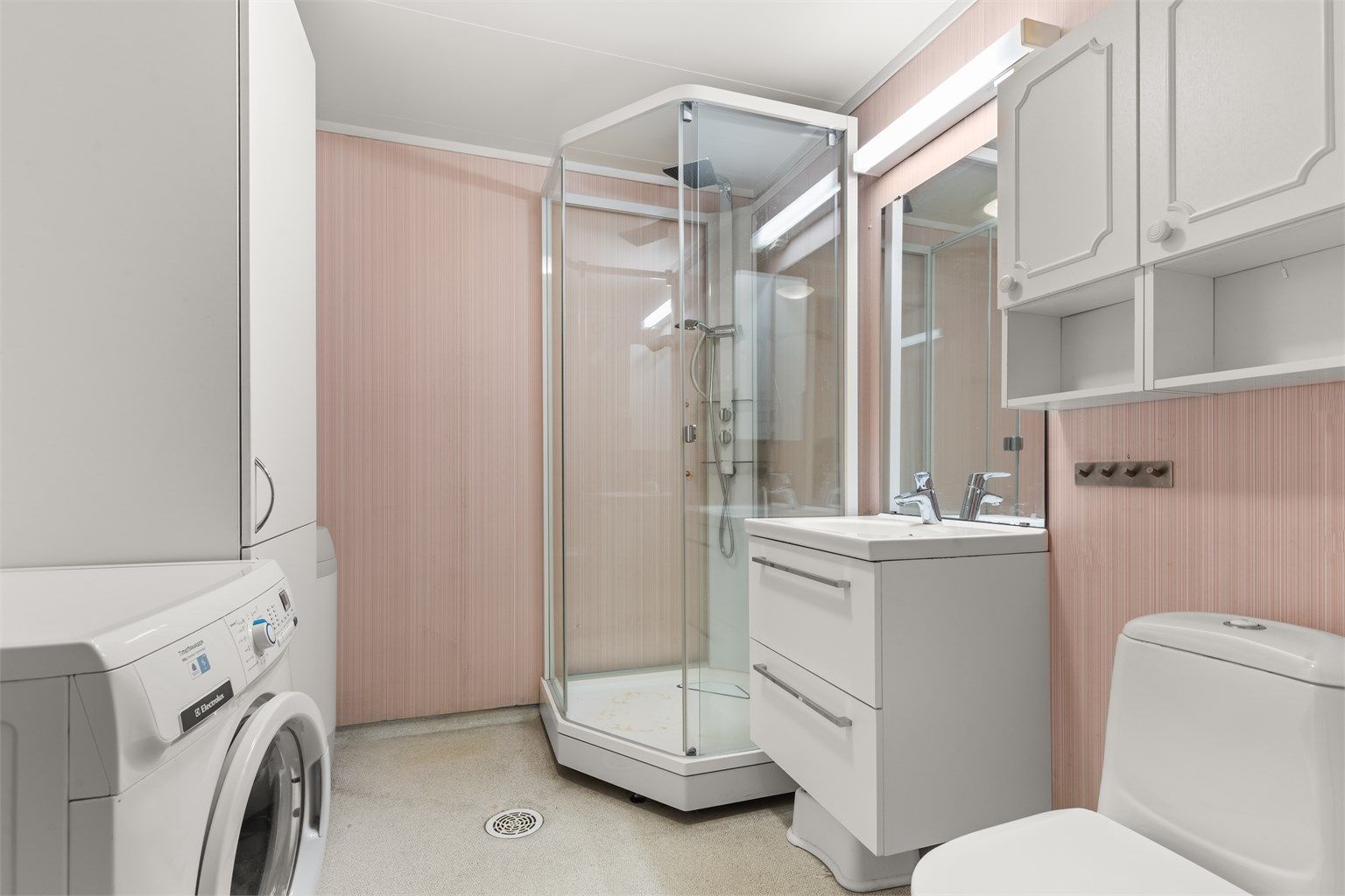 Badet er utstyrt med dusjkabinett, opplegg for vaskemaskin og elektrisk gulvvarme. Rommet har et betydelig oppgraderingsbehov og representerer en spennende mulighet til å etablere et moderne bad etter egen smak.