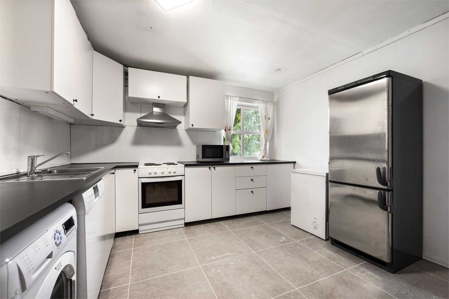 Kjøkkeninnredning med slette fronter fra 2017, benkeplate med laminert flate og nedfelt oppvaskkum i rustfritt stål med ett-greps armatur.