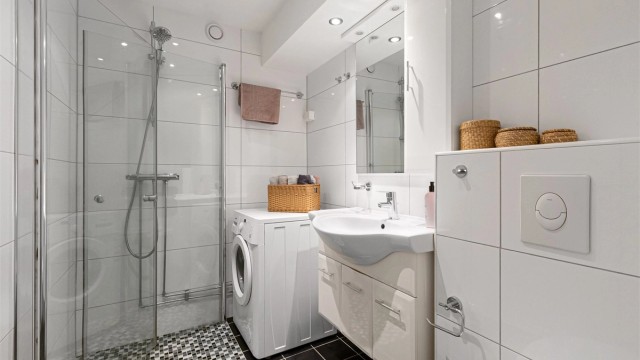 Pent baderom med fliser på gulv med gulvvarme, fliser på vegger og malt himling med downlights