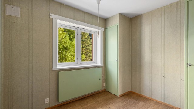 Soverom 2 med plassbygd garderobe og utsikt mot grønne omgivelser.