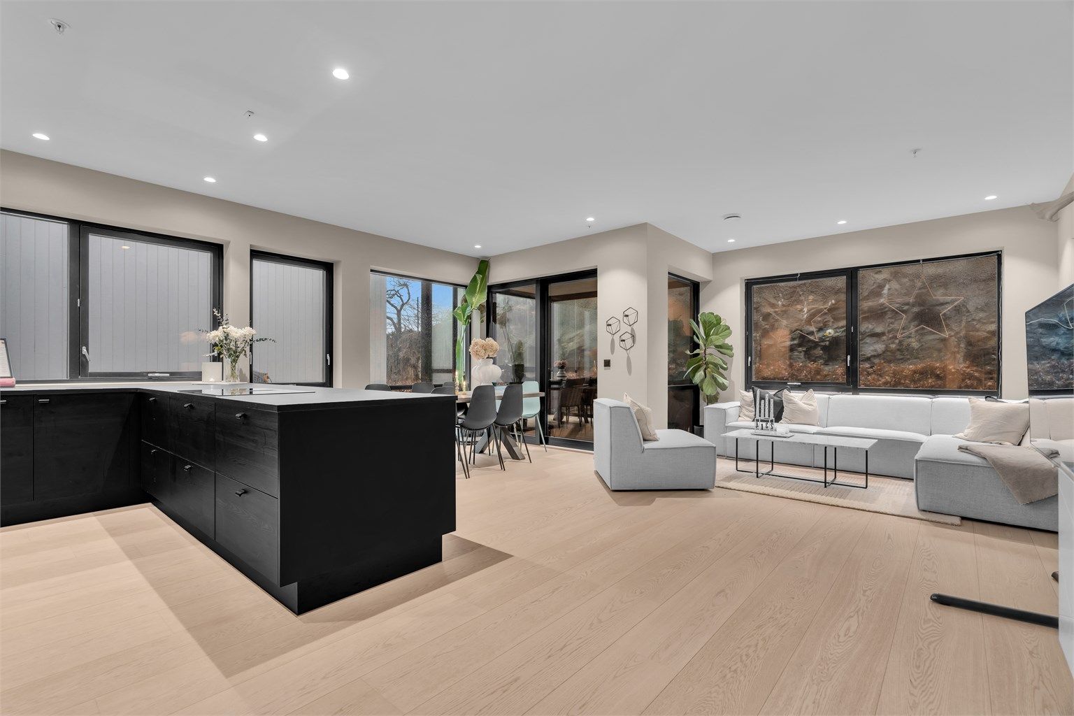 Lys stue med store vindusflater som slipper inn rikelig med dagslys.