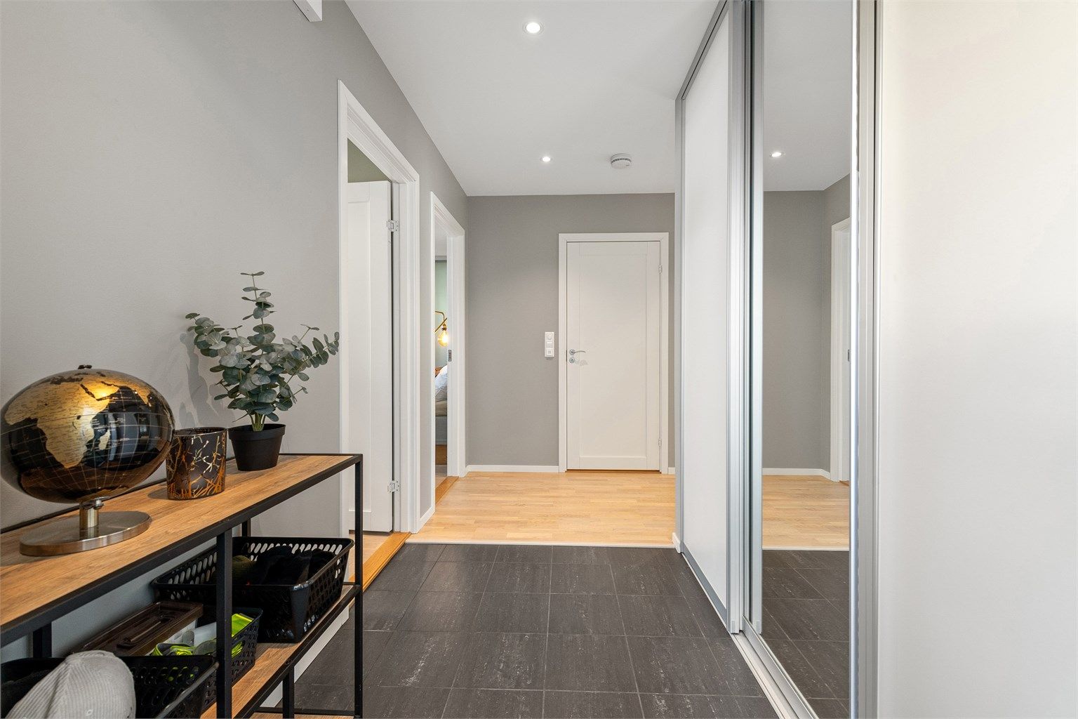 Innbydende entré med flislagt gulv med gulvvarme og god oppbevaringsplass i skyvedørsgarderobe.
