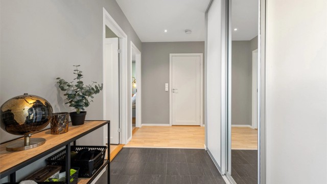 Innbydende entré med flislagt gulv med gulvvarme og god oppbevaringsplass i skyvedørsgarderobe.