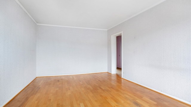 Romslig stue med plass til sofa, bord, TV og tilhørende møblement.