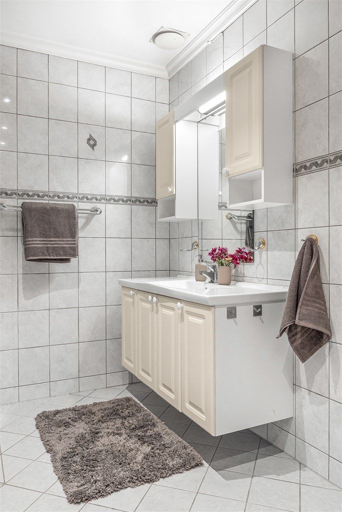 Baderomsinnredning med vegghengt servant, speil med overlys og ekstra skapplass.