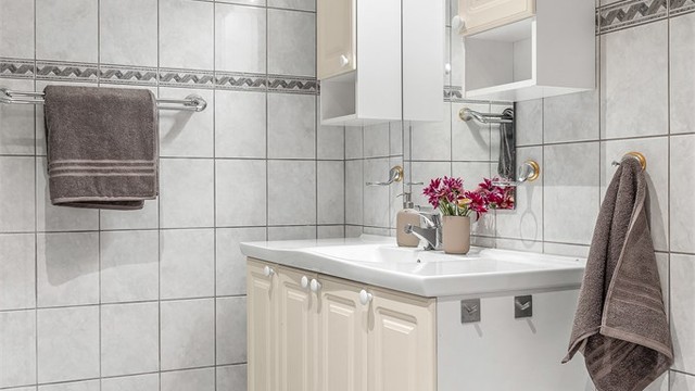 Baderomsinnredning med vegghengt servant, speil med overlys og ekstra skapplass.