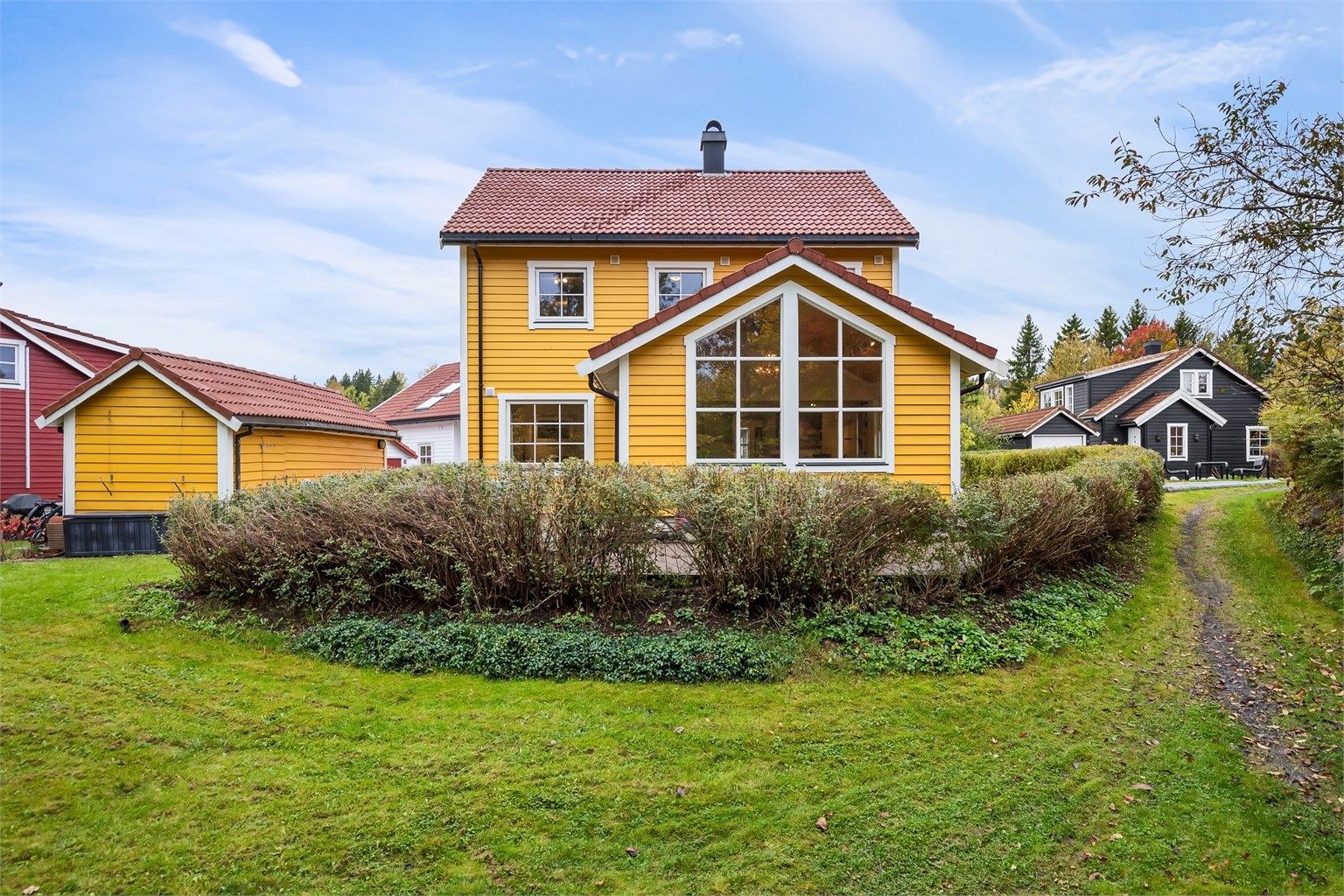 Pen hage med plen og hekk som skaper en lun og skjermet hageidyll.