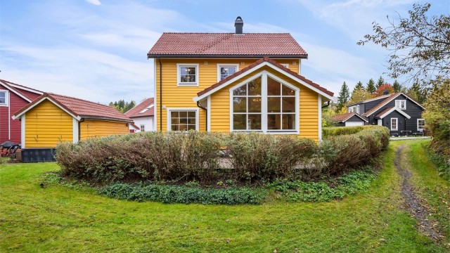 Pen hage med plen og hekk som skaper en lun og skjermet hageidyll.